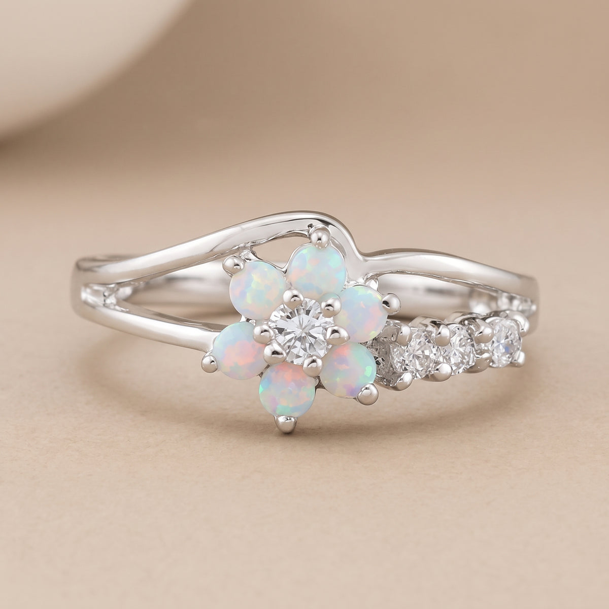 hero: A new photorealistic photograph, composed from scratch, of a piece of jewelry. The product rests on a seamless matte warm beige studio surface that smoothly transitions into a matching, softly graduated background. The atmosphere is quiet, neutral, and minimalist, with a neutral white balance. The ring is placed with its natural orientation, centered horizontally and positioned slightly below the vertical center of the frame. The complete ring is visible, occupying approximately 68% of the image widt…