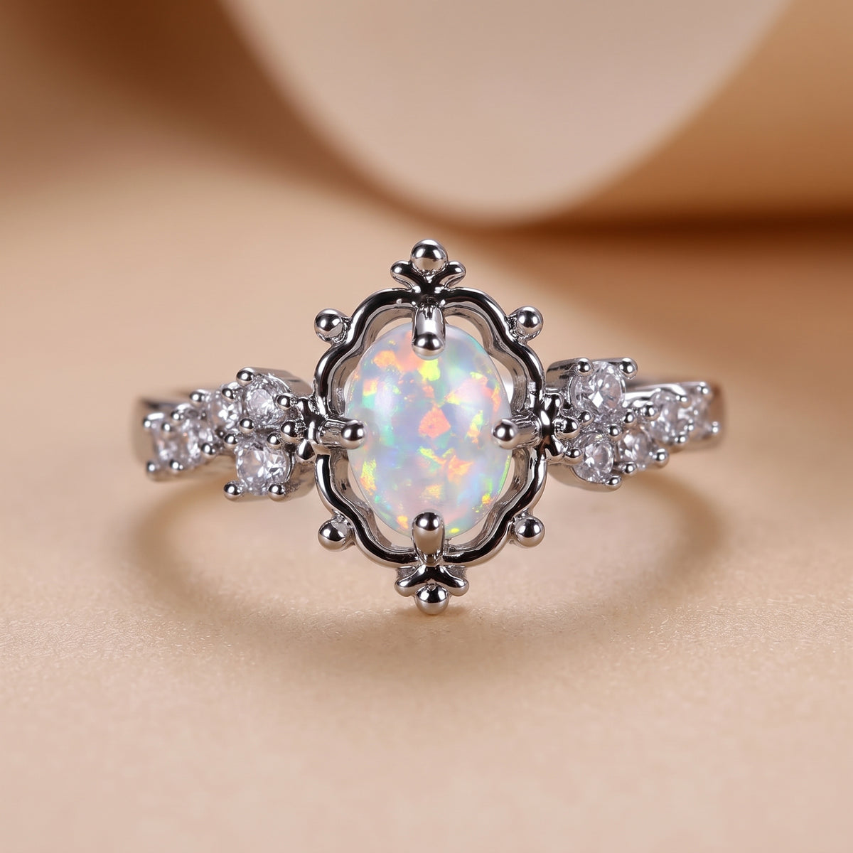 hero: A new photorealistic photograph of the product. The product rests on a seamless matte warm beige studio surface that gently curves into a matching softly graduated background. The ring is centered horizontally and positioned slightly below the vertical center. Captured with a straight-on eye-level camera angle, using a 100mm macro lens and a shallow depth of field (f/2.8) to ensure sharp focus on the product while providing soft background separation. Illumination comes from one large, soft diffused…